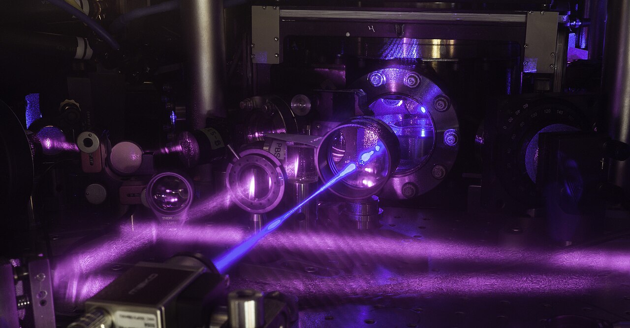 A blue laser beam crossing optics on a bench in a laboratory at JILA in Colorado, part of a strontium atomic clock photographed in 2017 (not one of the new nuclear clocks)