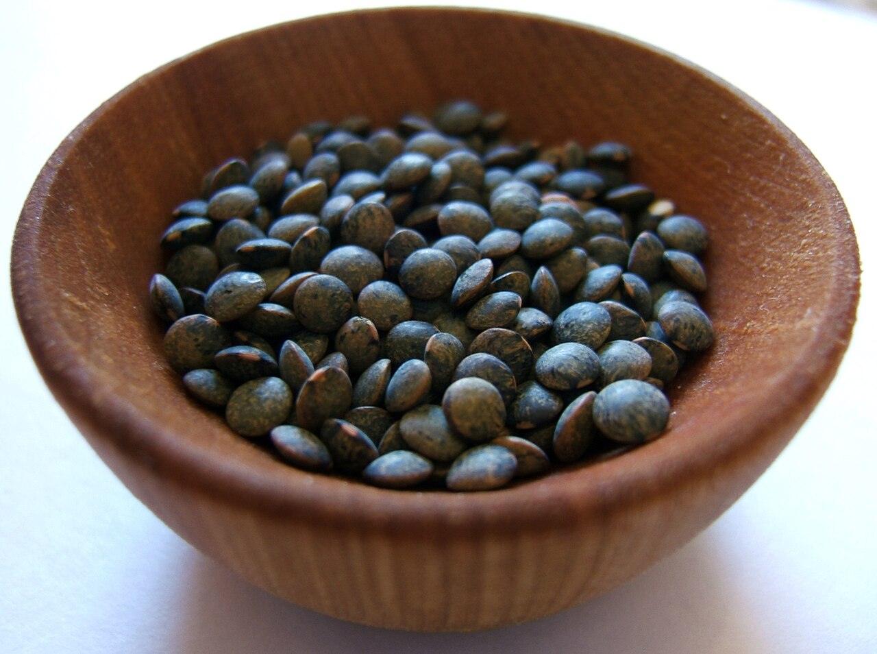 Dried green Puy lentils in a small wooden bowl