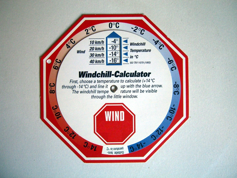 A round windchill calculator card with a red wind sign and a window that shows the wind chill temperature for a chosen air temperature and wind speed