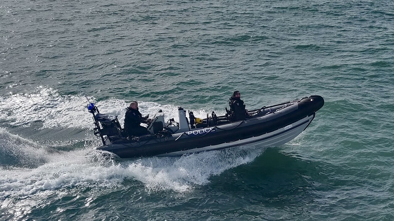 Two police officers on board a police rigid inflatable boat travelling through open water in the Solent