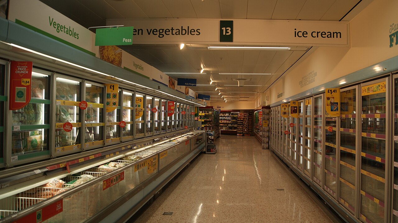 A supermarket aisle lined with glass-fronted fridge and freezer cabinets