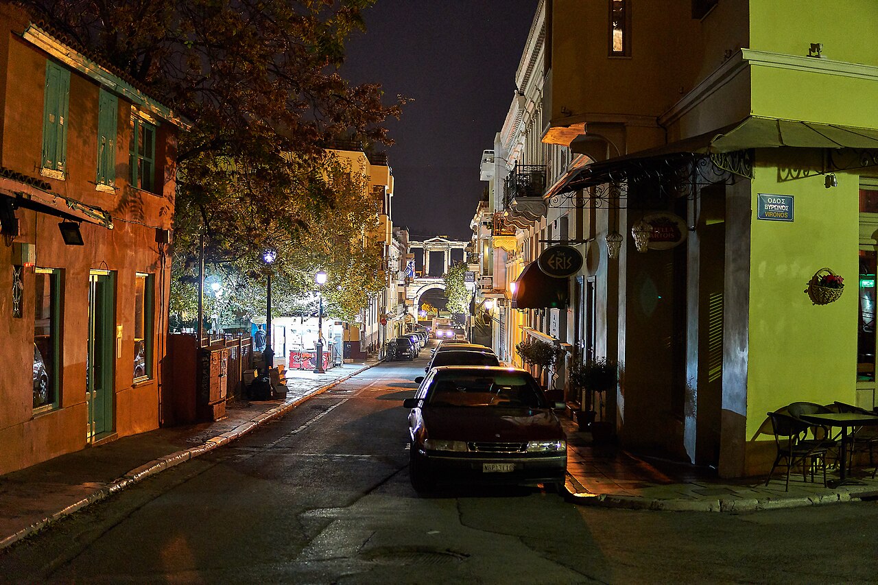 Lysikratous Street in the Plaka district of Athens at night, lined with parked cars and old houses