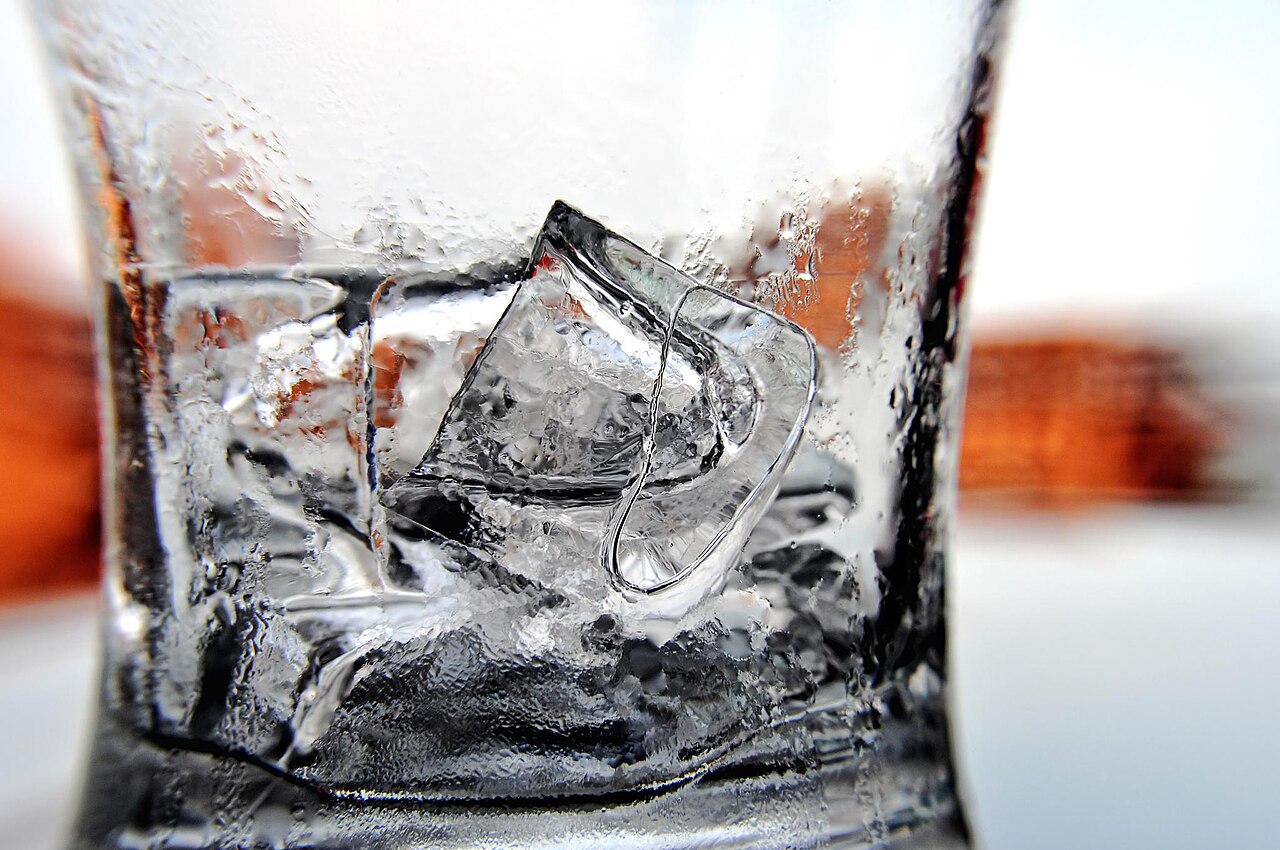 A close-up of ice cubes melting in a glass of water