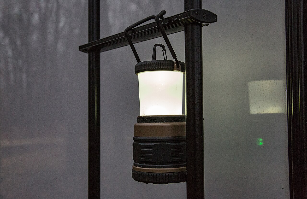 A battery-powered LED lantern glowing against a dark window