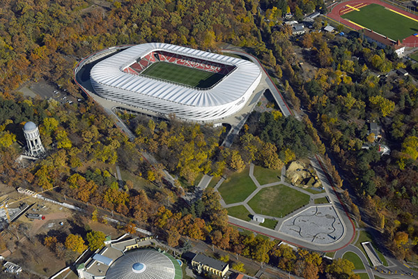 Aerial view of the Nagyerdei Stadion in Debrecen, Hungary, surrounded by autumn woodland