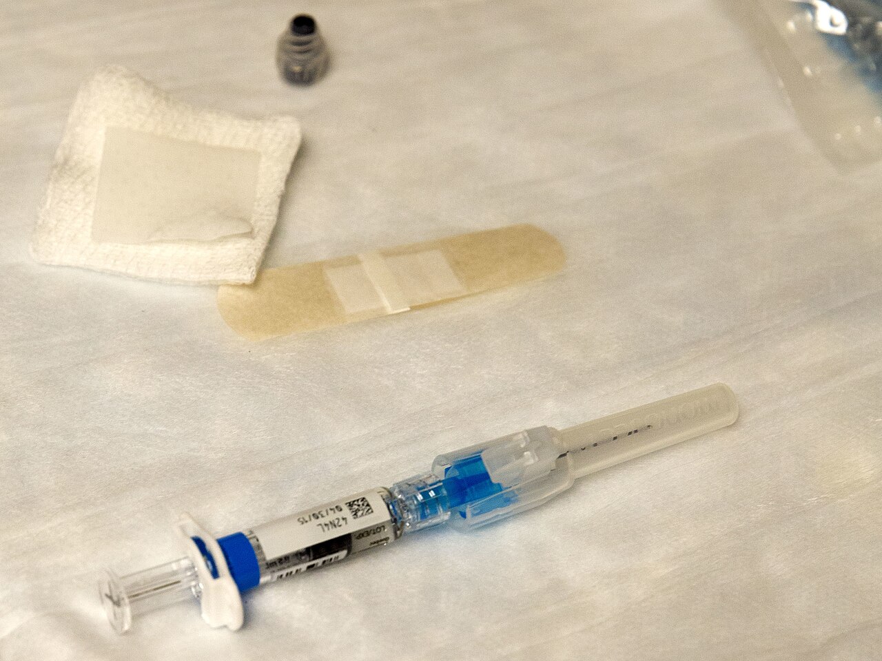 A prefilled influenza vaccine syringe on a table beside a bandage and gauze before a vaccination event