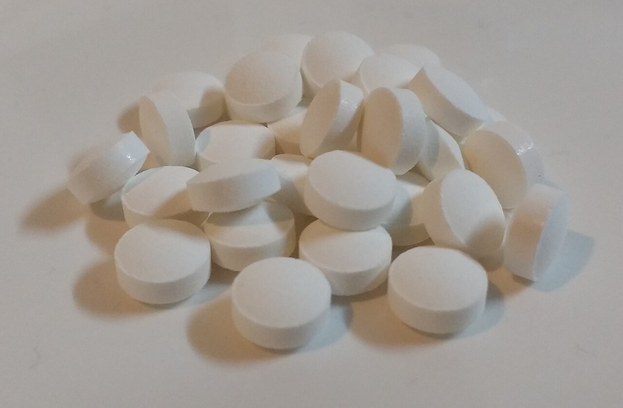 A pile of white zinc supplement tablets on a plain surface