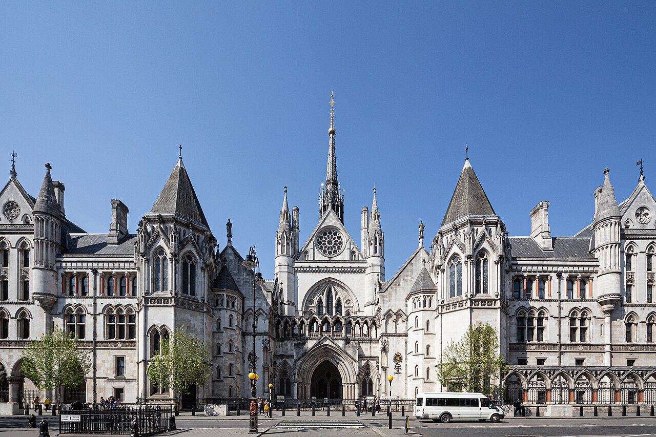 The Gothic stone frontage of the Royal Courts of Justice on the Strand in London under a clear blue sky
