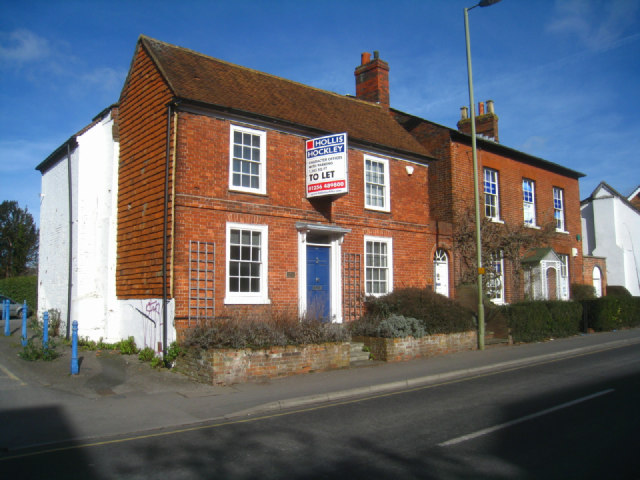 A letting agent's To Let board outside a brick house on an English street.