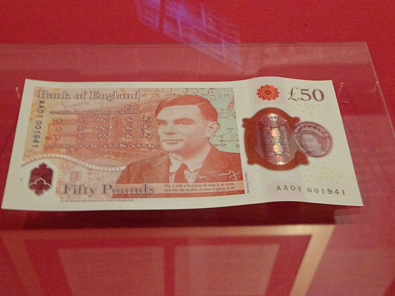 A Bank of England £50 polymer banknote showing a portrait of Alan Turing, lying face up under glass