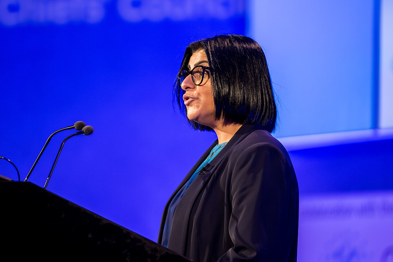 Home Secretary Shabana Mahmood speaking at a lectern in front of a blue stage backdrop