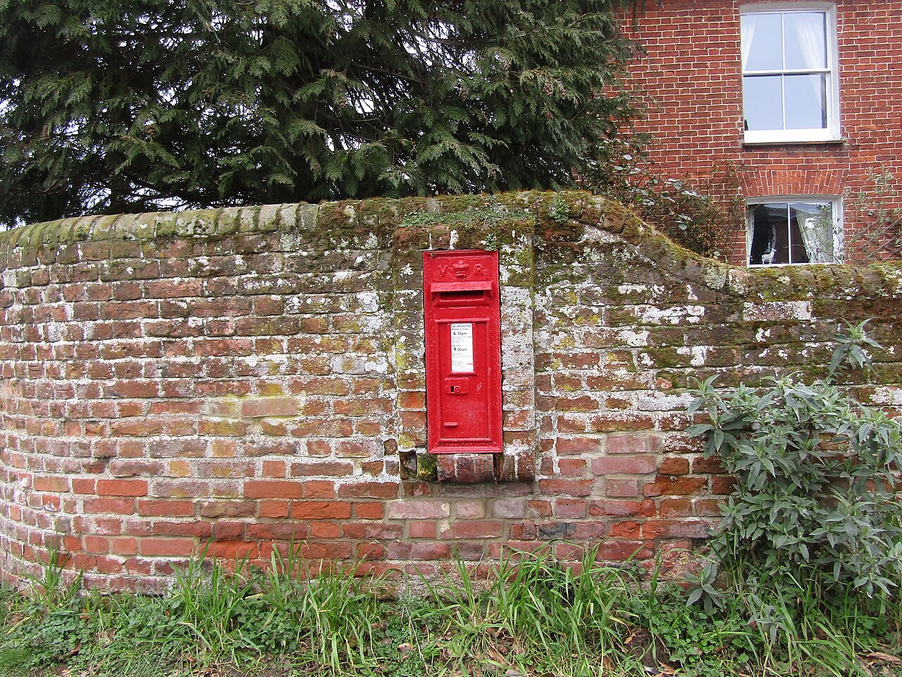 A red Royal Mail post box set into a brick wall