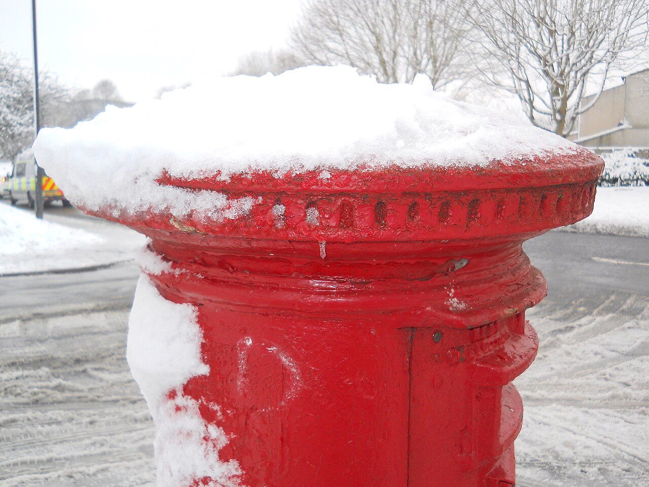 A red pillar box with a cap of snow on top