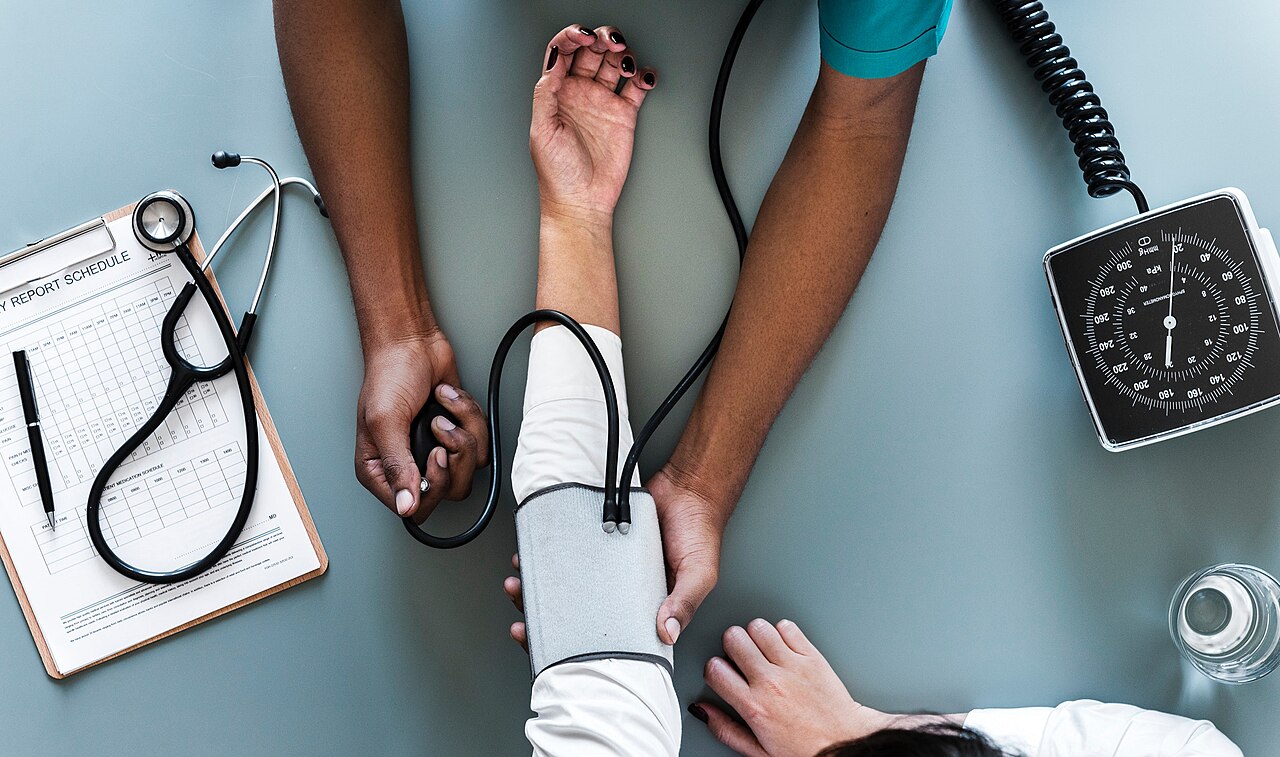 A healthcare worker measuring a patient’s blood pressure with a cuff and dial gauge