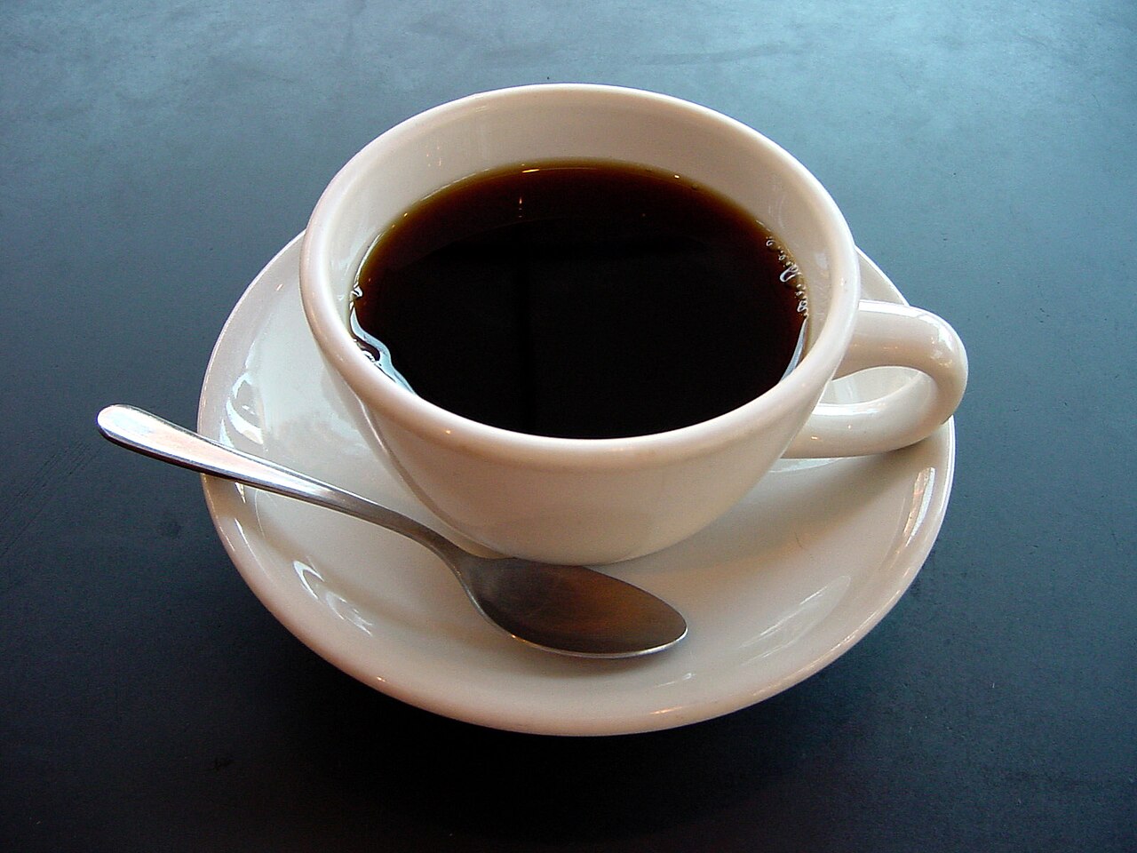 A small cup of black coffee on a saucer