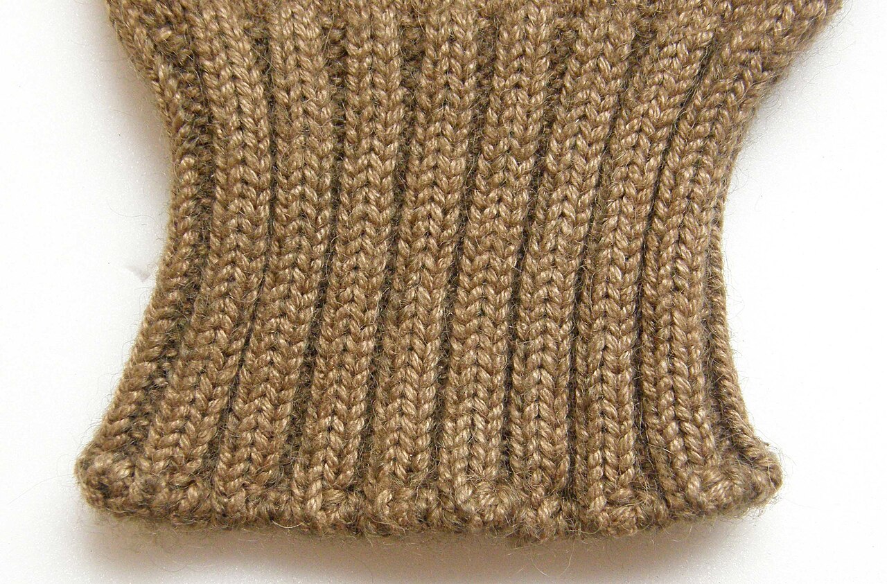 The knitted ribbed cuff of a brown woollen glove