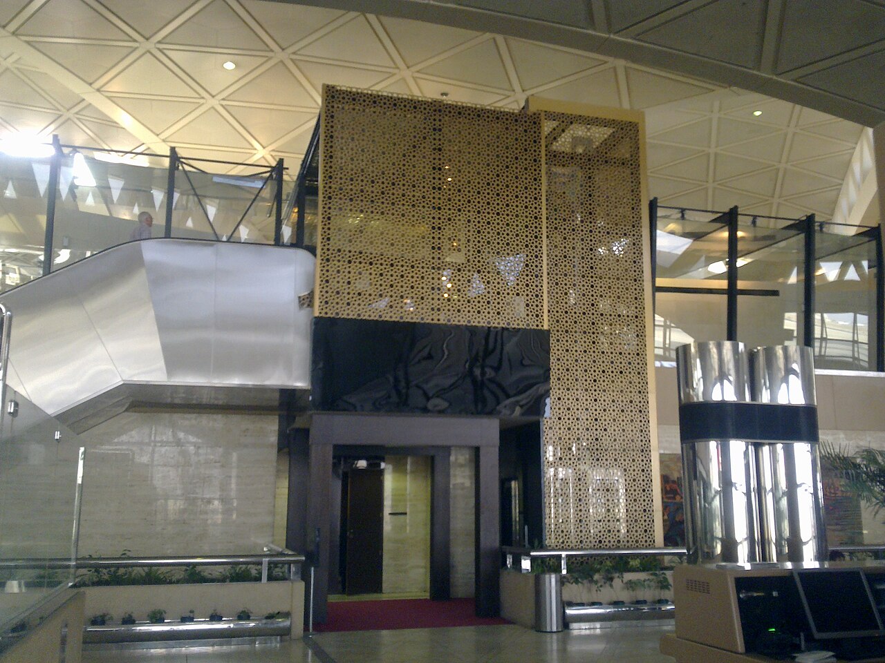Archive photo of a terminal interior at King Khalid International Airport in Riyadh, with escalators and a gold lattice screen, taken in 2012