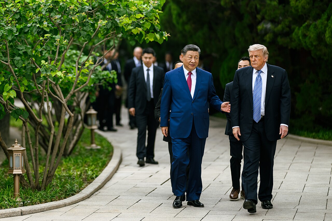 Xi Jinping and Donald Trump walking side by side along a garden path in Beijing during Trump’s visit to China in May 2026, with officials behind them