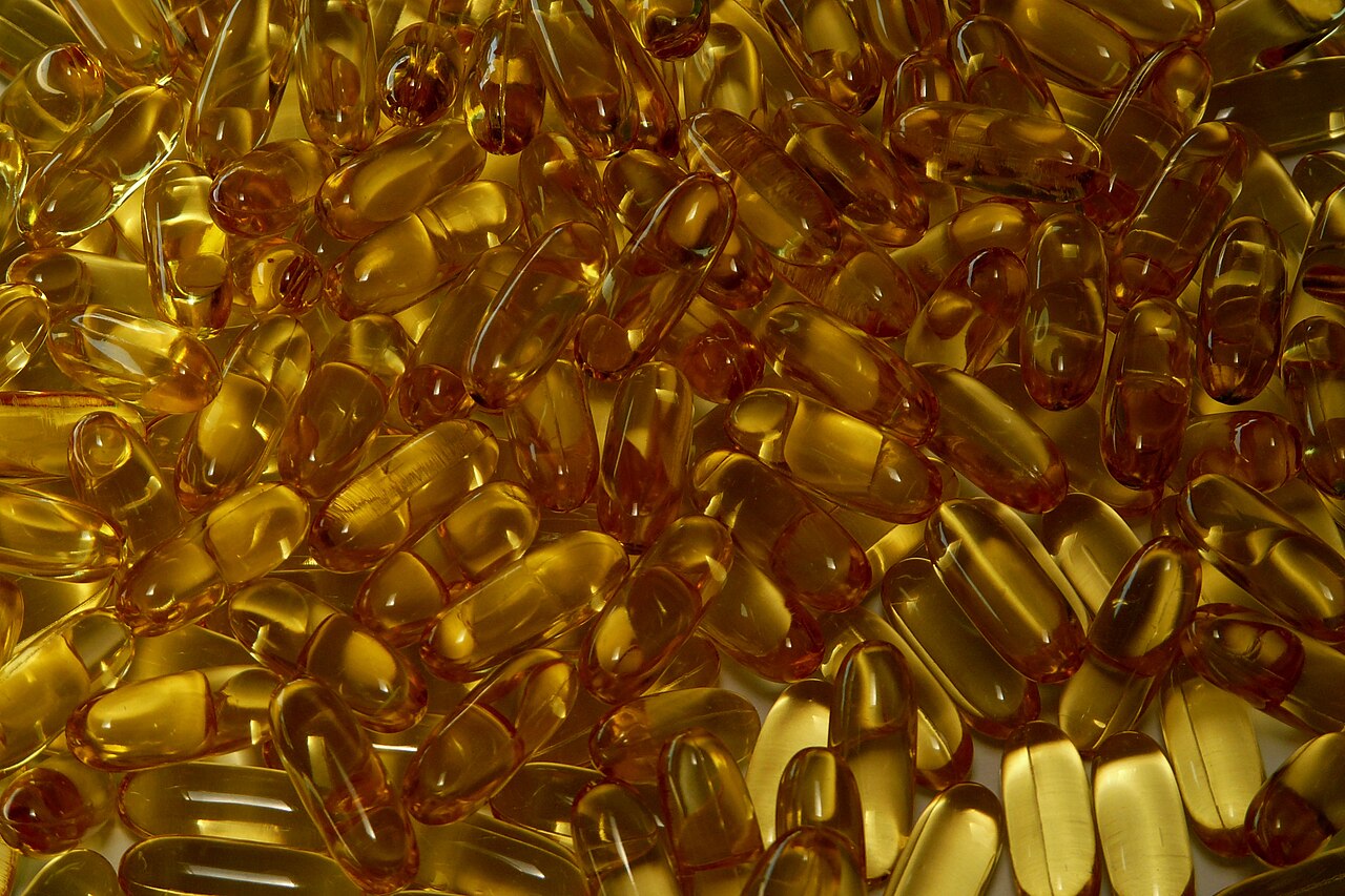 A close-up pile of amber-coloured fish oil supplement capsules