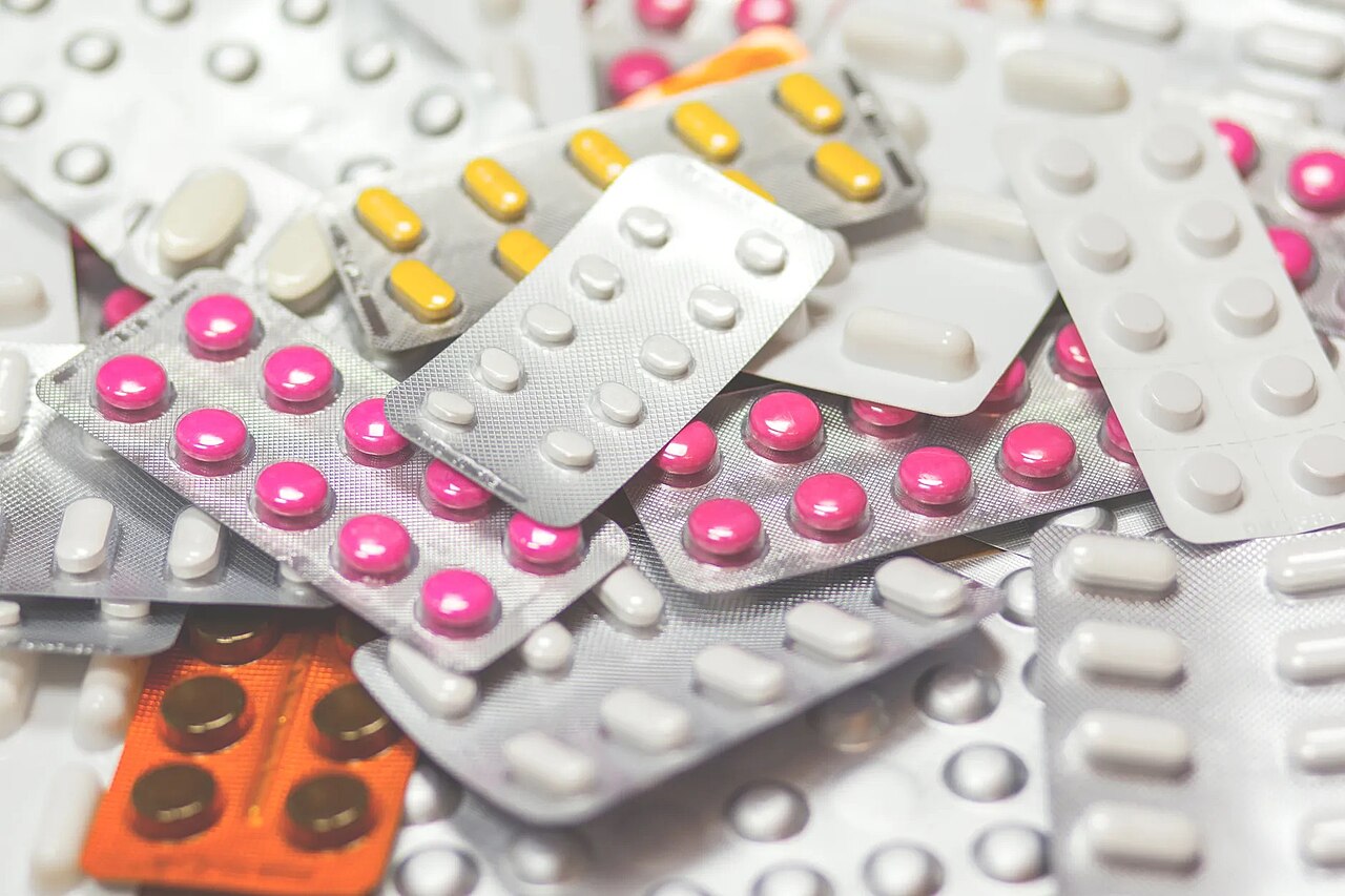 A pile of foil blister packs of pink, yellow and white pills