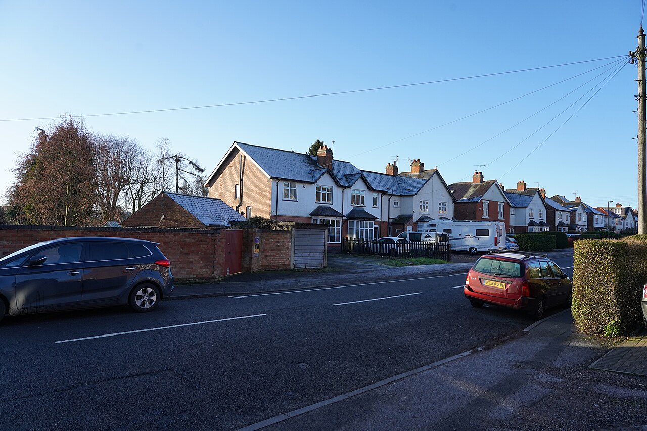 Frost on the roofs of a row of houses along a road, with cars parked in winter sunshine.