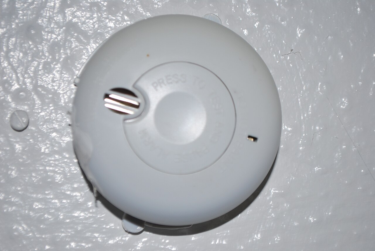 A round white smoke alarm with ‘press to test’ lettering on its central button