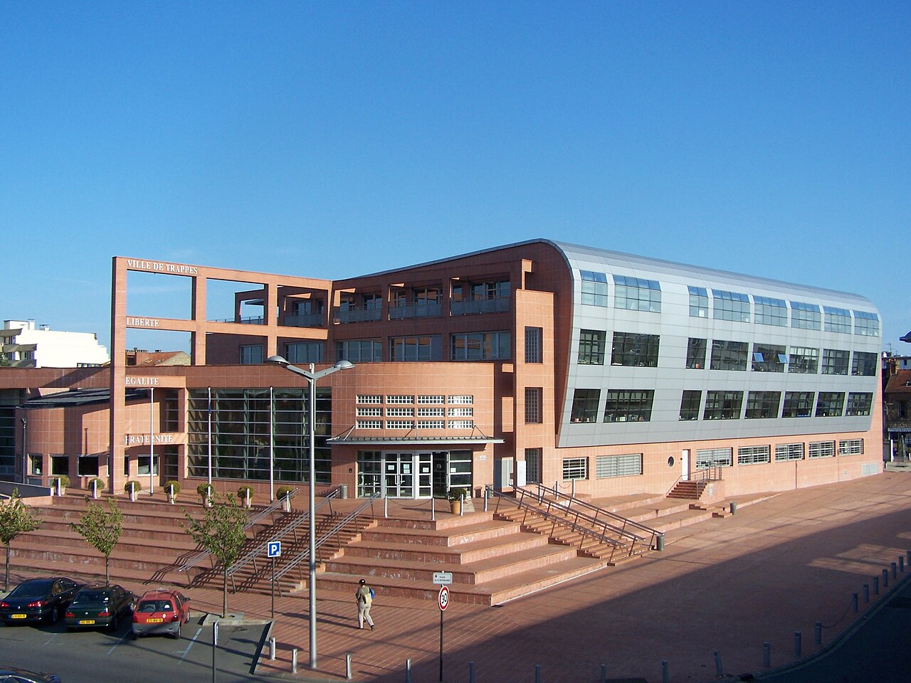 The town hall of Trappes, France, a brick-red and silver building with the words Ville de Trappes, Liberté, Egalité and Fraternité on its facade