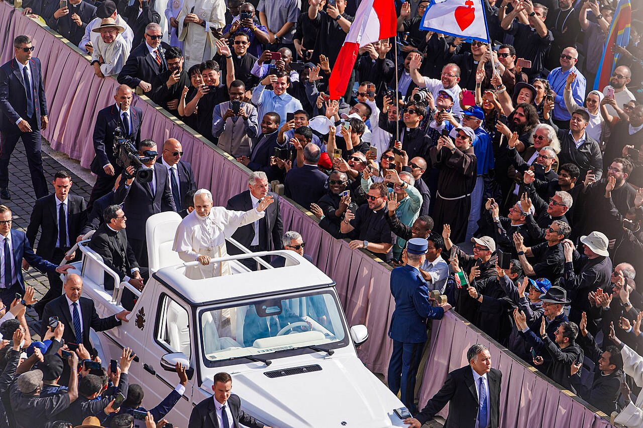 Pope Leo XIV waves from a popemobile to crowds at his inauguration Mass in Vatican City in May 2025