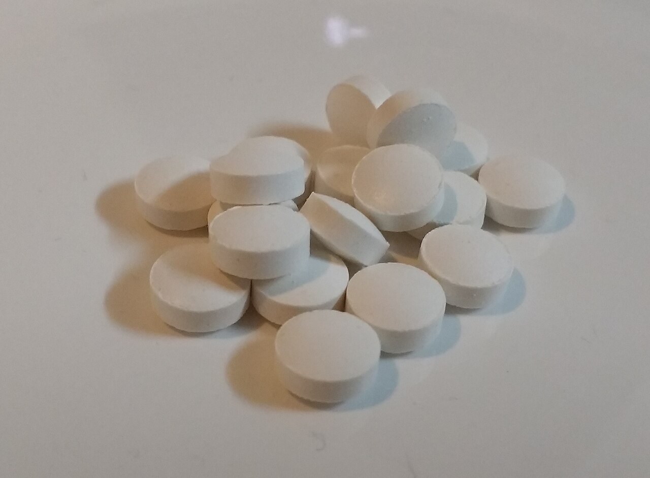 A small pile of white vitamin D tablets on a white surface