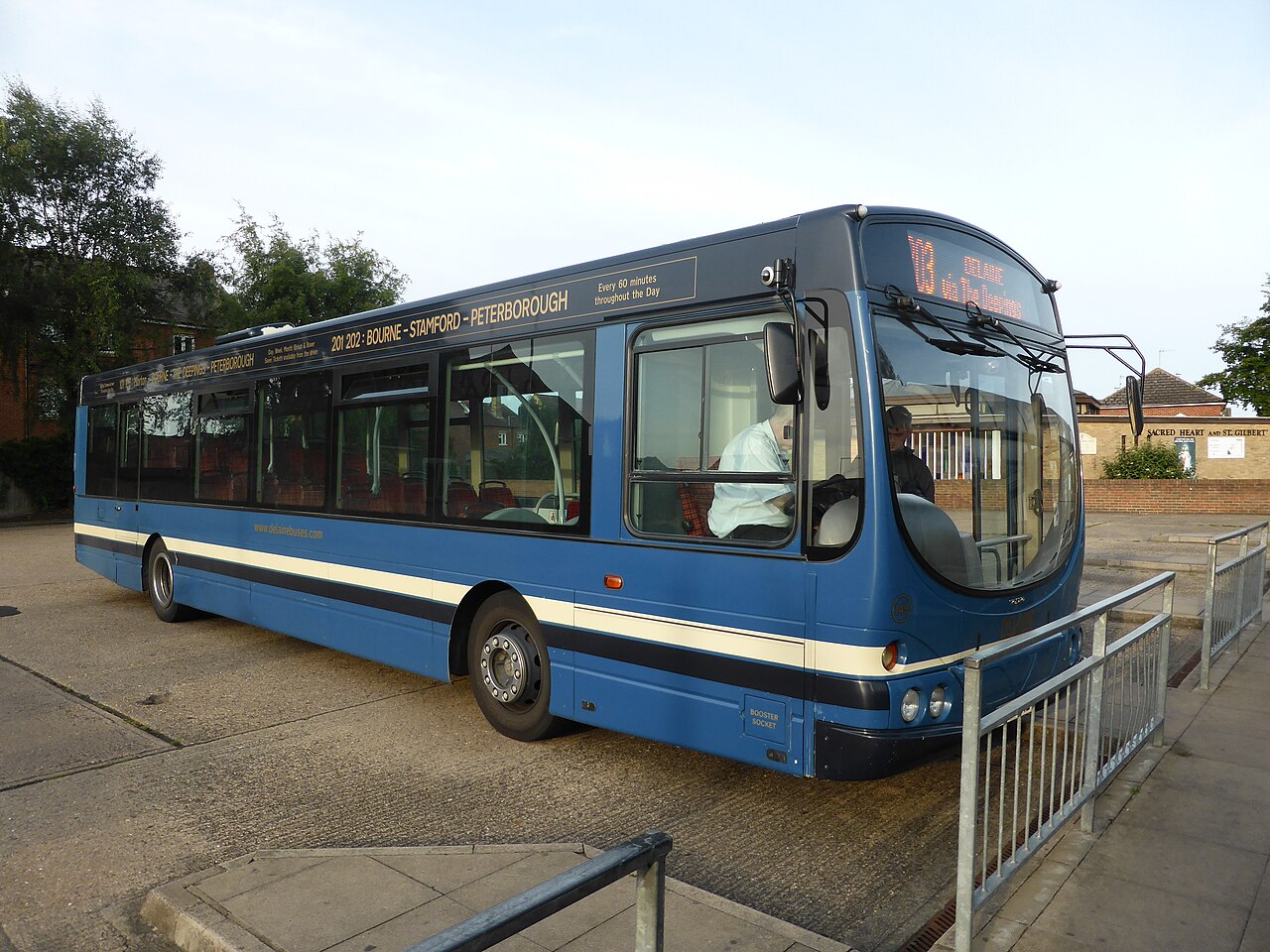 A blue single-decker bus at Bourne bus station, its route board reading Bourne – Stamford – Peterborough