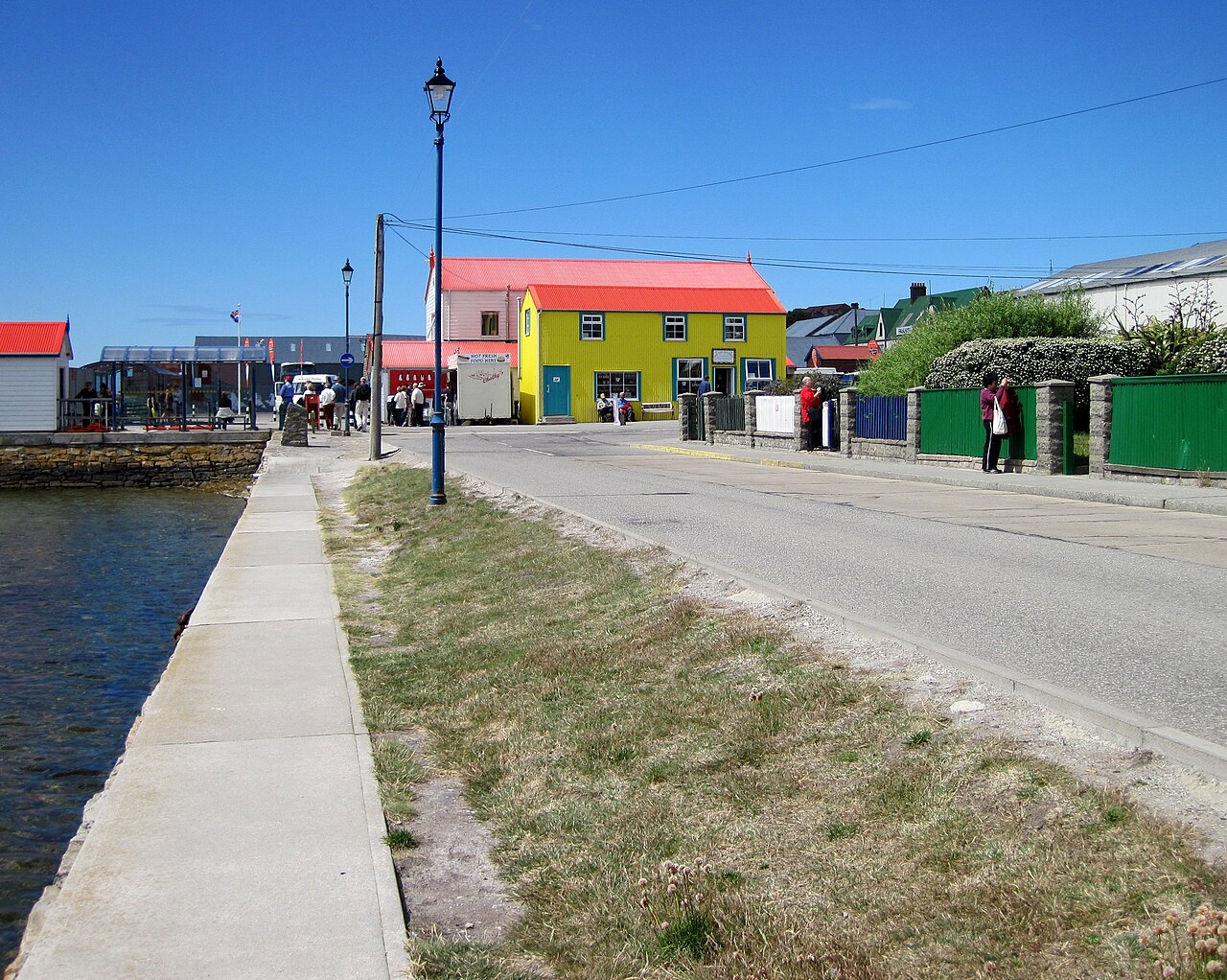 The waterfront road in Stanley, capital of the Falkland Islands, with brightly painted buildings beside the harbour.