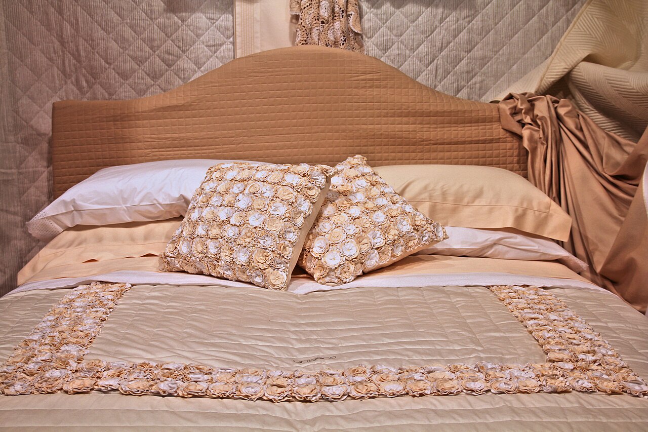 A made double bed with pillows and a beige bedspread