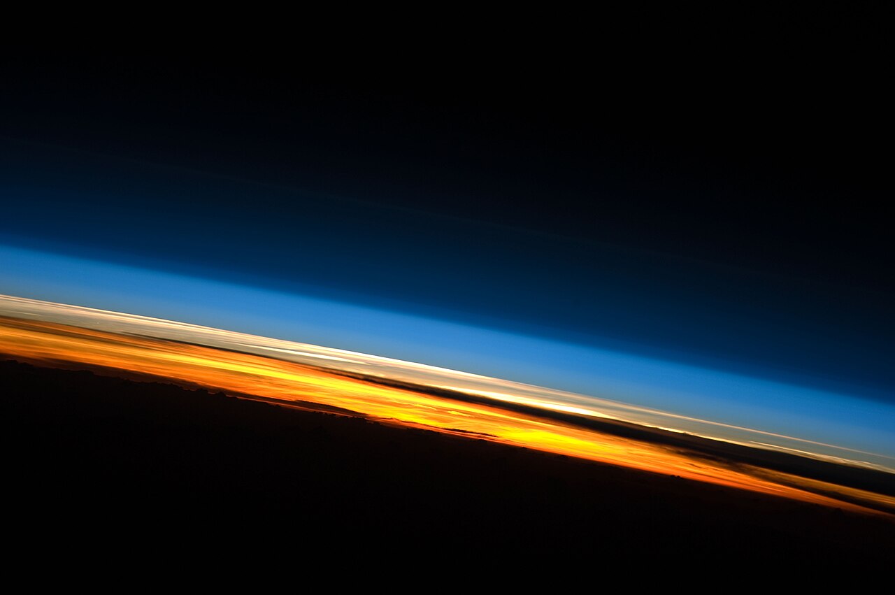 Sunset over the Indian Ocean photographed from the International Space Station, with a blue band of atmosphere above a glowing orange horizon